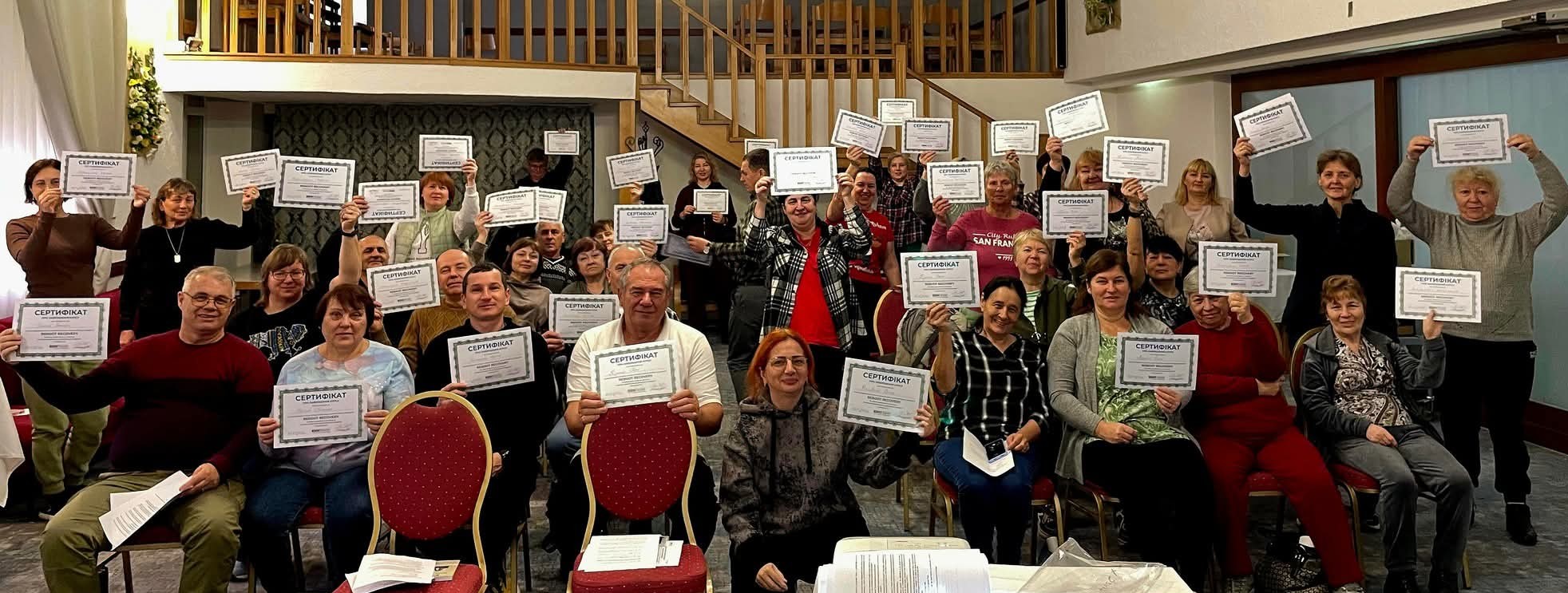 Ukrainian training participants hold their certificates in a group photo.