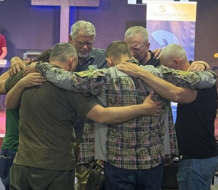 A group of men pray together at a Reboot gathering.