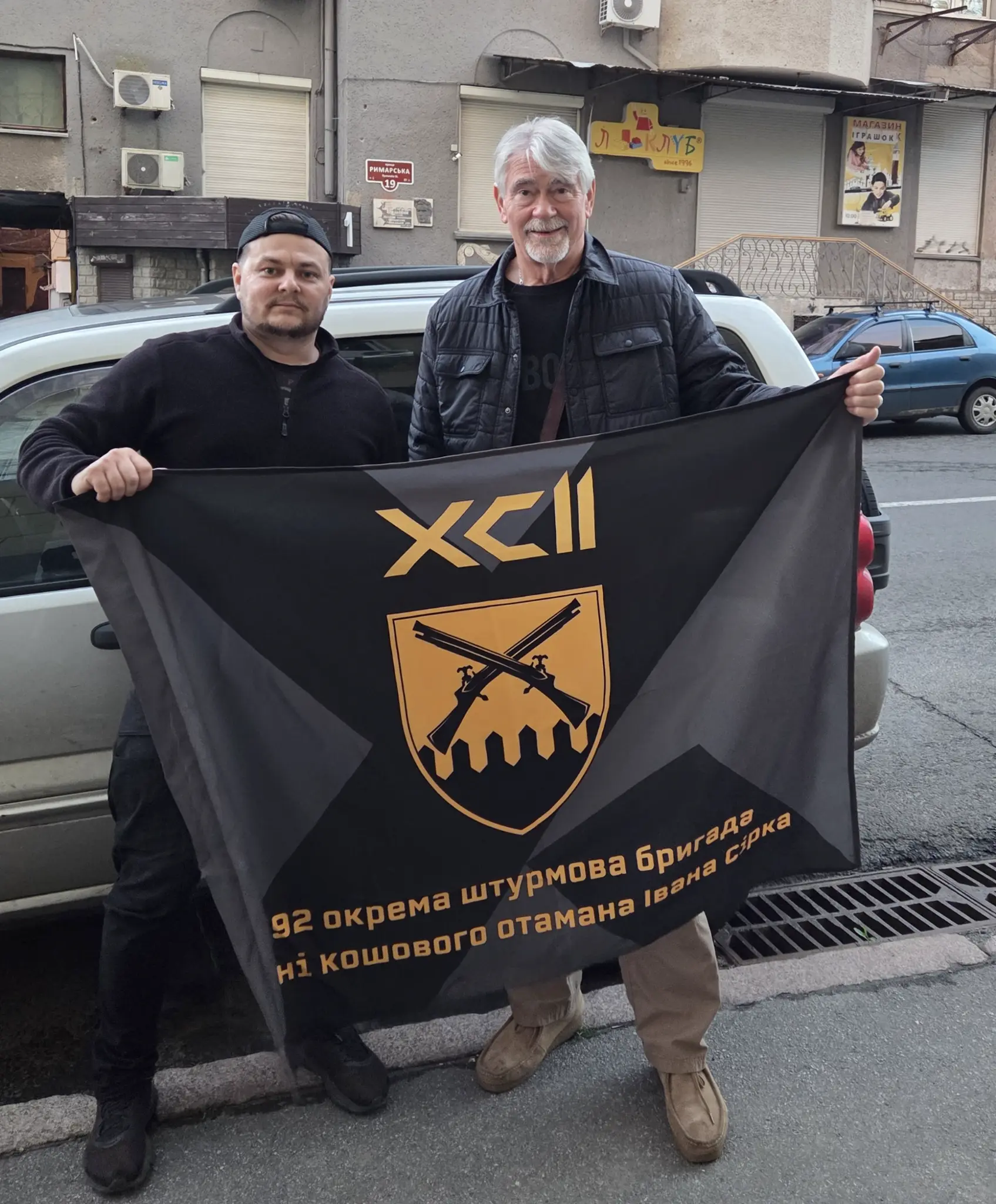 Chris holding a flag with a Ukrainian brigade representative.